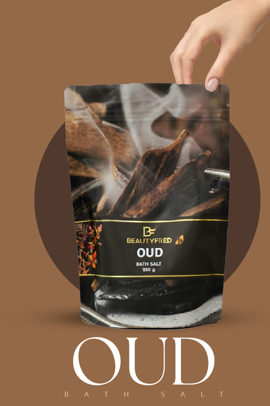 Oud bath salt packaging with a hand holding it against a brown background