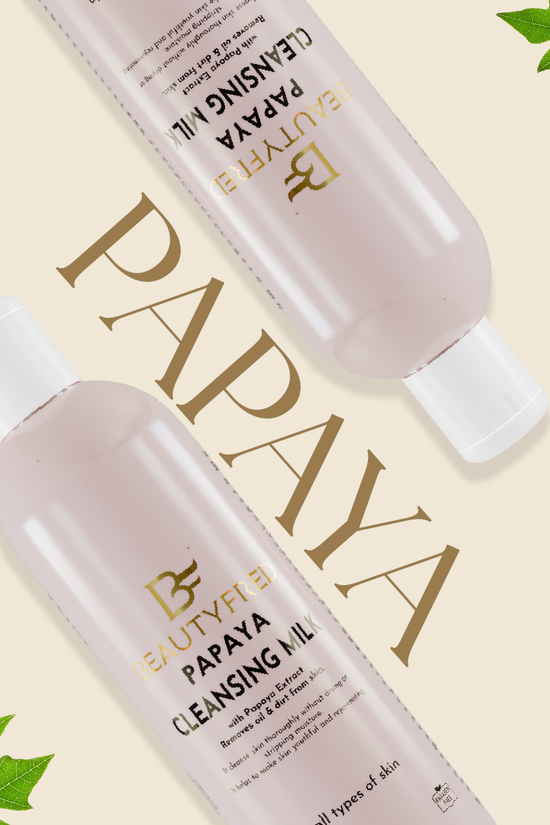 Two bottles of Beauty Bay Papaya Cleansing Milk on a beige background with green leaves.
