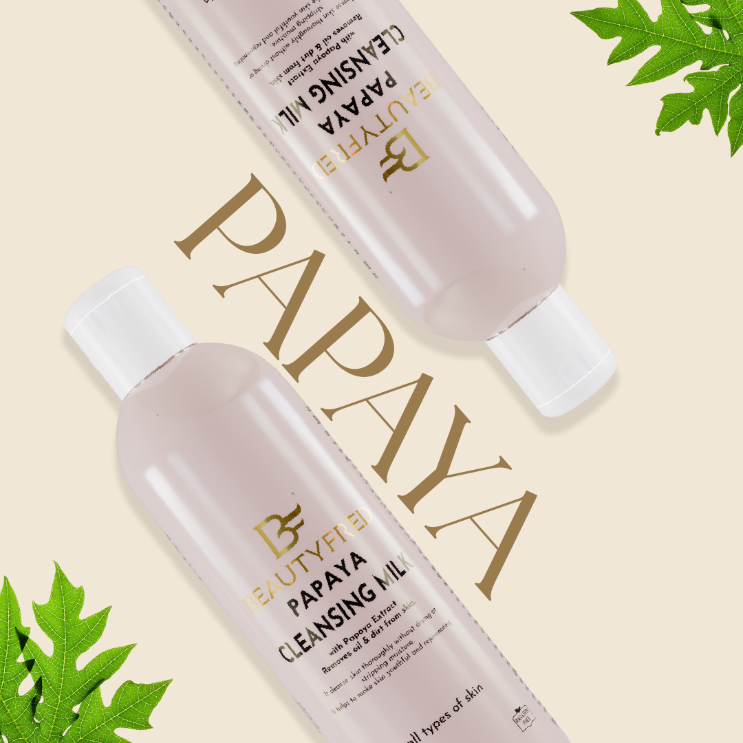 Two bottles of Beauty Bay Papaya Cleansing Milk on a beige background with green leaves.