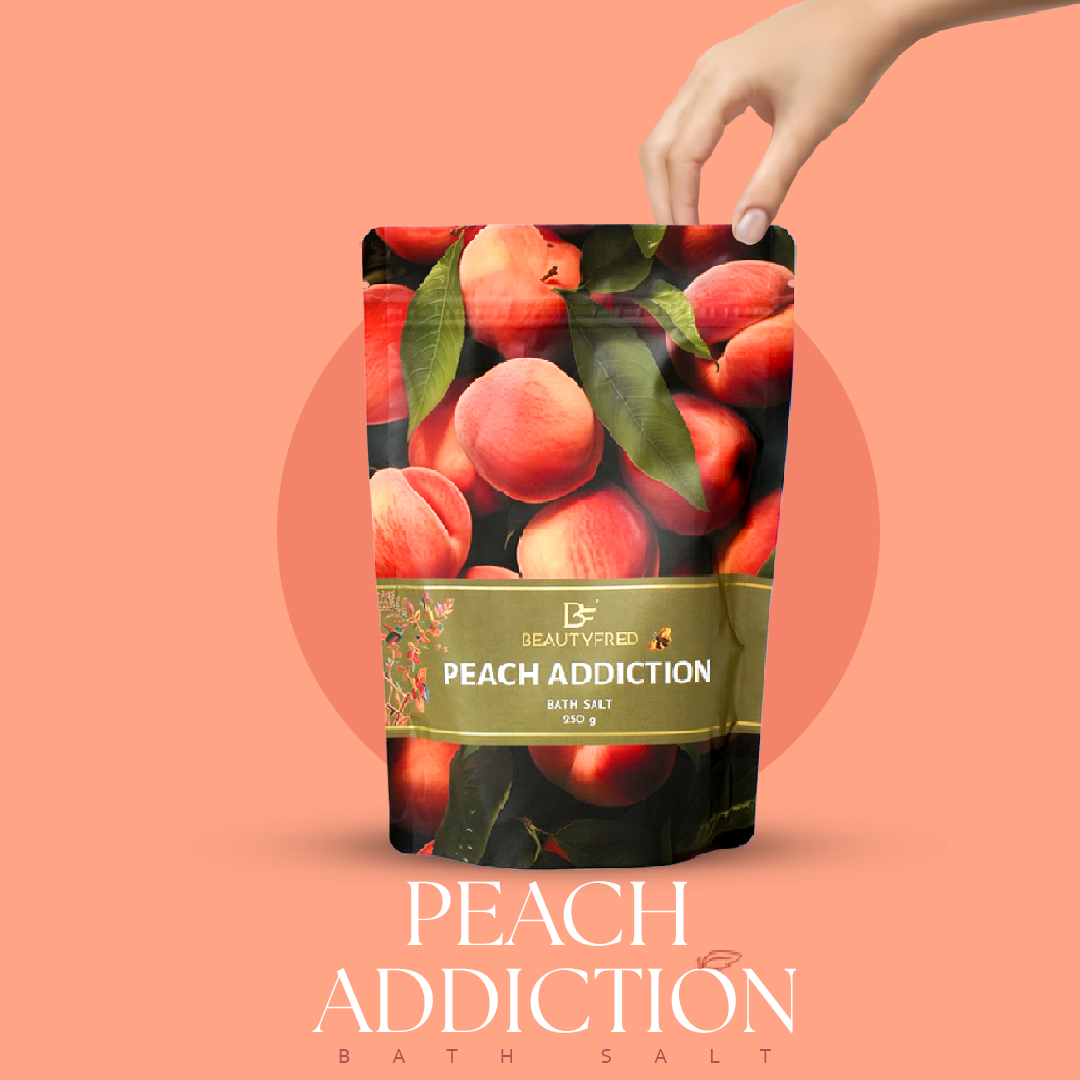 Peach Addiction bath salt packaging with a hand holding it against a peach-colored background