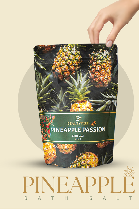 Pineapple-themed bath salt packaging with a hand holding it against a beige background