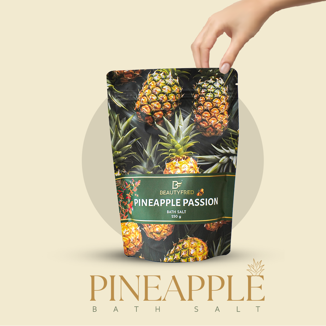 Pineapple-themed bath salt packaging with a hand holding it against a beige background
