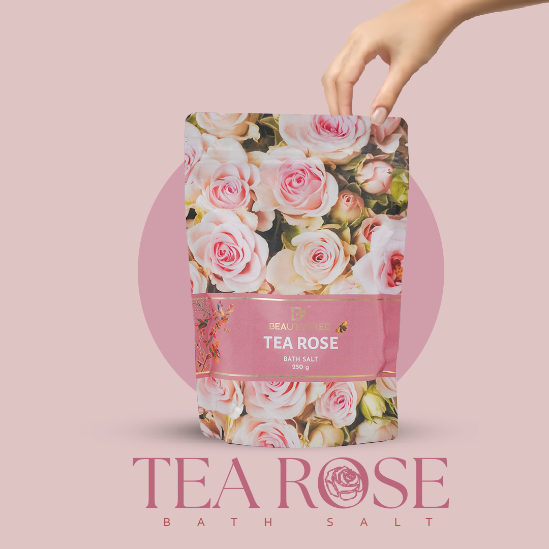 Tea Rose bath salt packaging with a hand holding it against a pink background