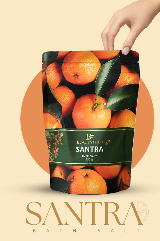 Hand holding a bag of Beautyfred Santra bath salt with orange design on a beige background